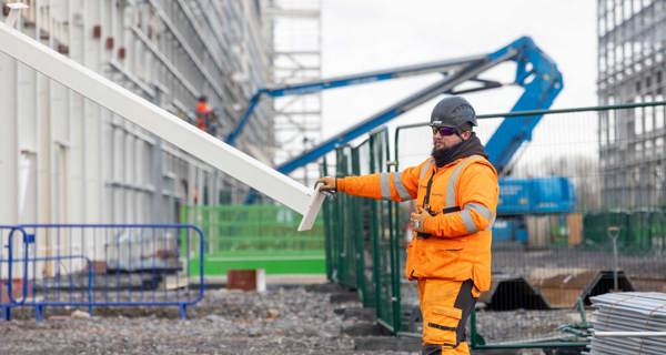 Construction worker guiding a steel beam as it's lifted