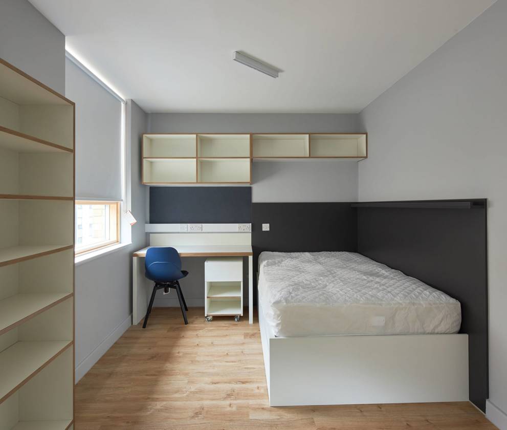 Modern student bedroom interior, featuring a work desk, bed, and ample storage space.
