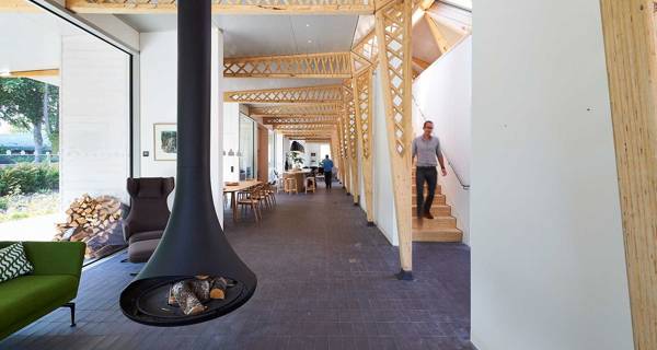 The central area at Maggie’s Manchester,  by the staircase with a large communal table, and plenty of natural light.