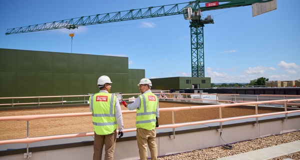 Two Sir Robert McAlpine employees chat with a tower crane in the background