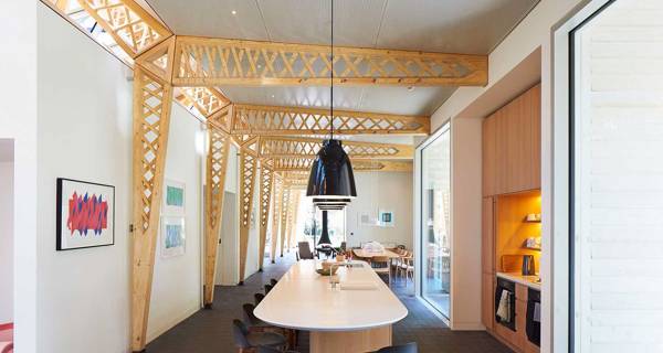 The central kitchen area at Maggie’s Manchester, with a large communal table, and plenty of natural light.