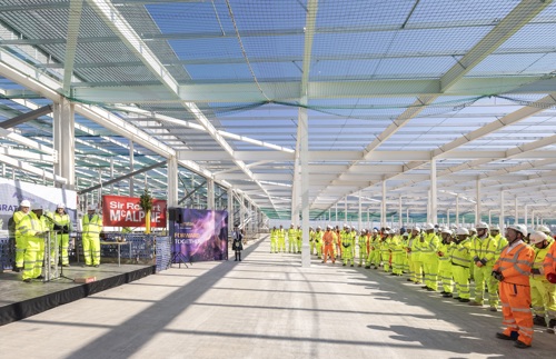 Workers gather at the ceremony while an official speaks at a lectern